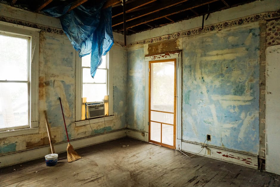 Home An empty room in an abandoned house with peeling walls and construction tools.